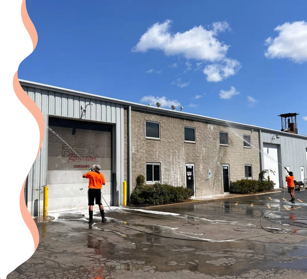 A man in an orange shirt is cleaning the outside of a building.